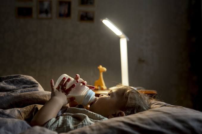 A warm mug of milk on a nightstand, representing soothing evening habits to improve sleep and reduce cravings